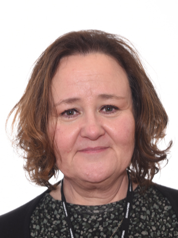 Nainen hymyilee ja katsoo kameraa päin.