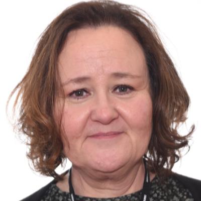 Nainen hymyilee ja katsoo kameraa päin.