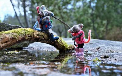 Huovutetut hiiret seikkailemassa veden äärllä. Toinen hiiri on ojentanut vedenrajassa seisovalle hiirelle oksan, ja auttaa toista ylös.
