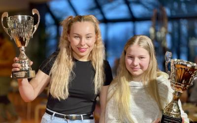 kaksi tyttöä pitelee pokaleita