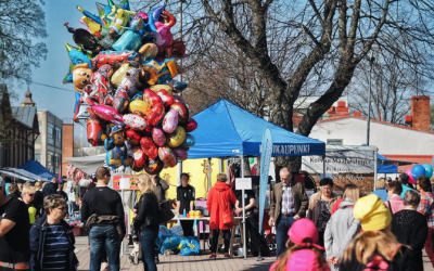 Paljon ihmisiä ja markkinakatoksia torilla, sekä iso rykelmä heliumilmapalloja leijumassa ilmassa.