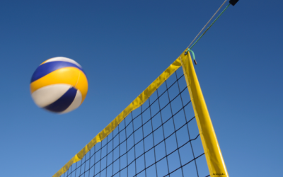 lentopallo lentämässä lentopalloverkon yläpuolella sinisellä taivaalla