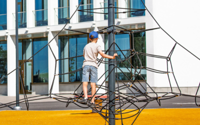 Lapsi kiipeää kiipeilytelineessä aurinkoisena kesäpäivänä.