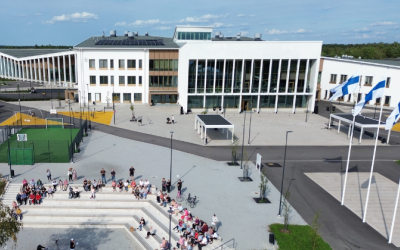Ilmakuva monitoimijatalo Wintteristä kesäisenä päivänä. Rakennuksen edustalla liehuu Suomen liput ja ulkoportailla istuu ihmisiä.
