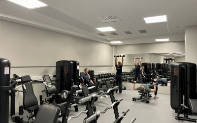 kuntosalin yleiskuva, jossa kolme naista treenaa