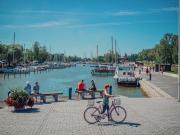 Kalaranta kesällä 2021, kuvassa veneitä, ihmisiä istumassa kaupungilahden rannalla, etualalla ihminen taluttaa pyörää.