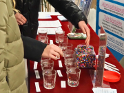 Kädet laittavat pieniä hamahelmiä lasikippoihin.