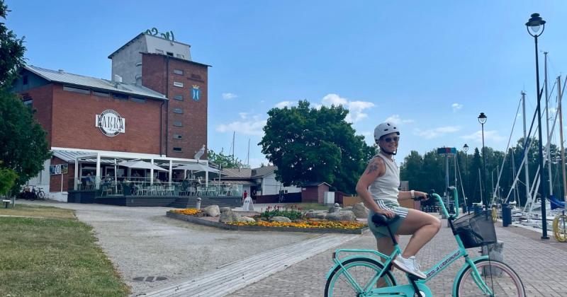nainen pyörän kanssa kaupungin rannalla