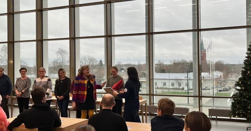 vammaisneuvoston juhlassa kunniakirjan jako taustalla kaupunki ikkunan takaa