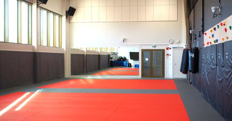 budosali jossa taustalla peilit sivuilla kiipeilyseinä ja nyrkkeilysäkit