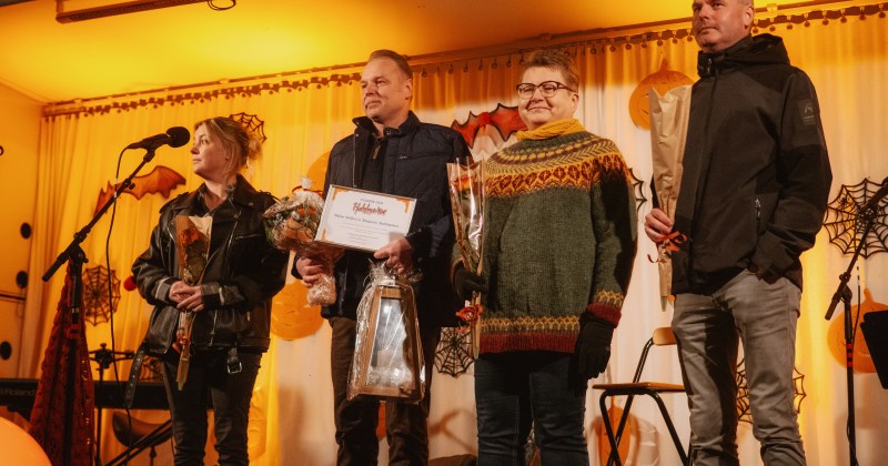 Ihmiisä rivissä valaistulla lavalla.